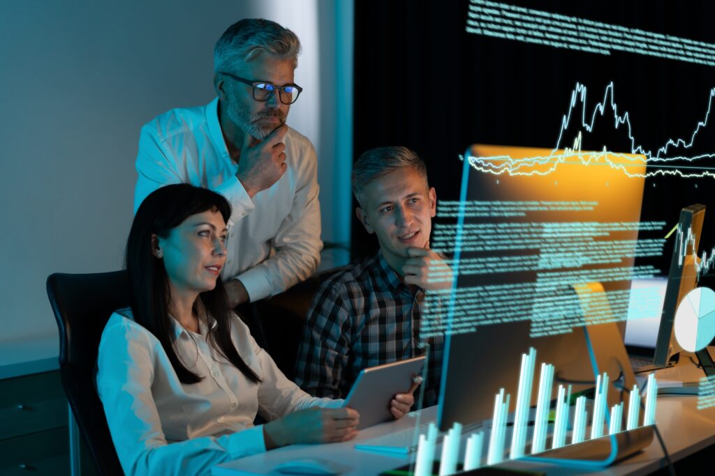 Team,Of,Business,Professionals,Analyzing,Data,And,Graphs,On,Computer