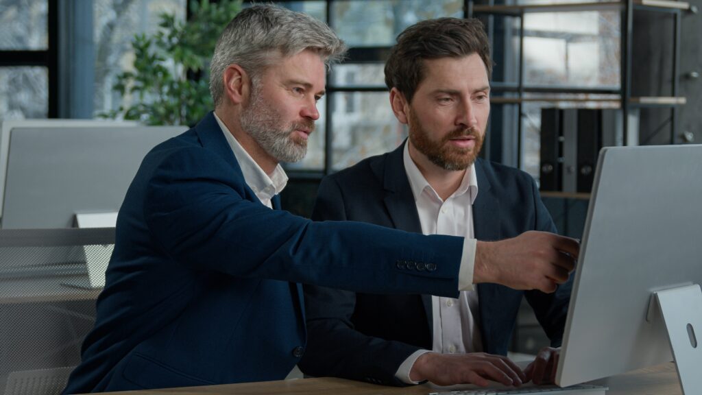 Mature,Businessman,Mentoring,Man,Discussing,Project,On,Computer,Consulting,Investor